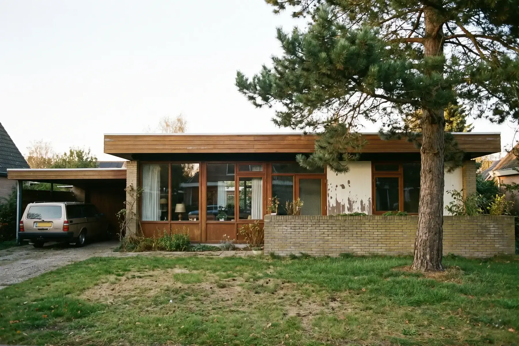Bungalow uit de jaren zestig met een plat dak, grote ramen en een grasveld