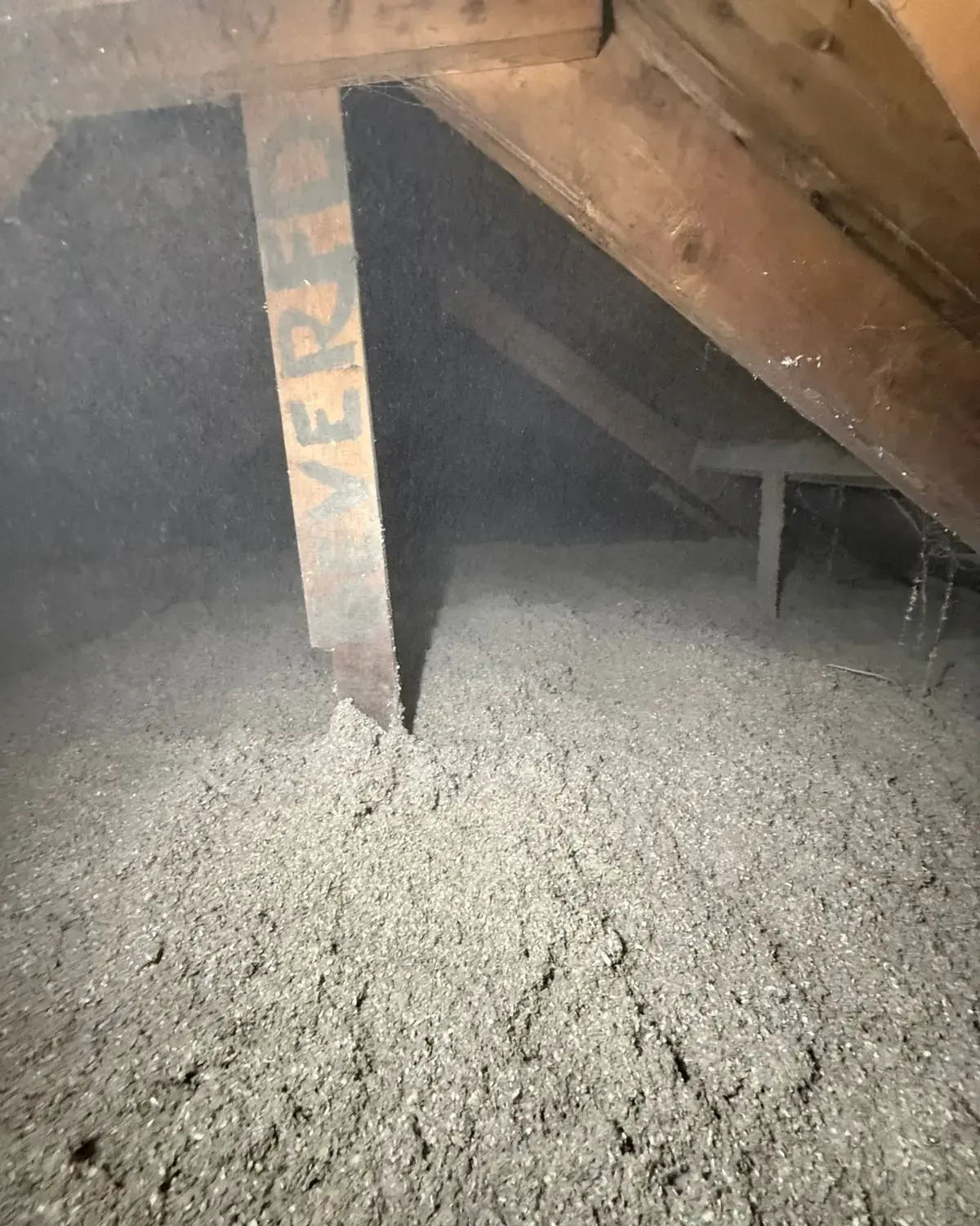 Losse cellulose ligt als een dikke laag op de vloer van de ruimte boven het plafond