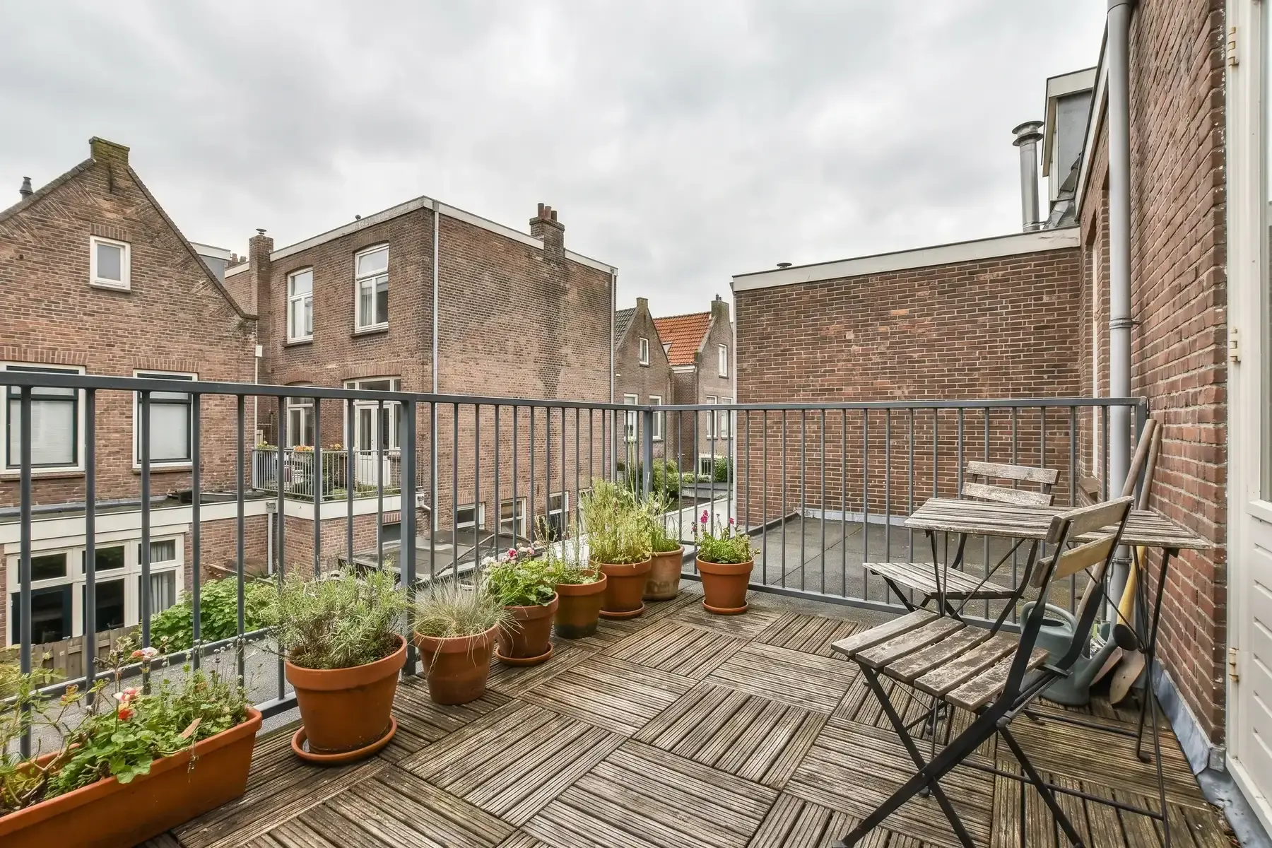 Klein dakterras op een uitbouw achter een stadswoning, met tegels en planten