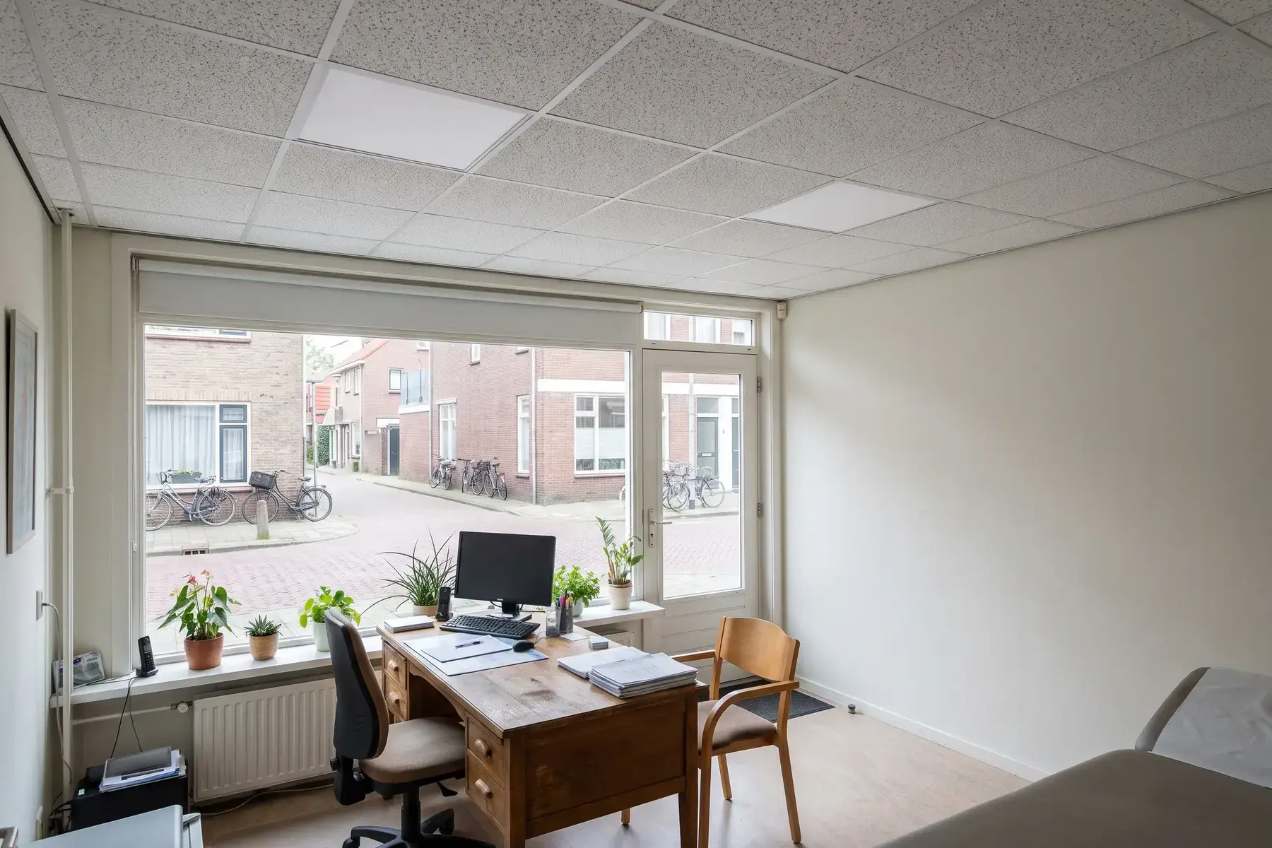 Praktijkruimte op de begane grond met een systeemplafond van witte tegels
