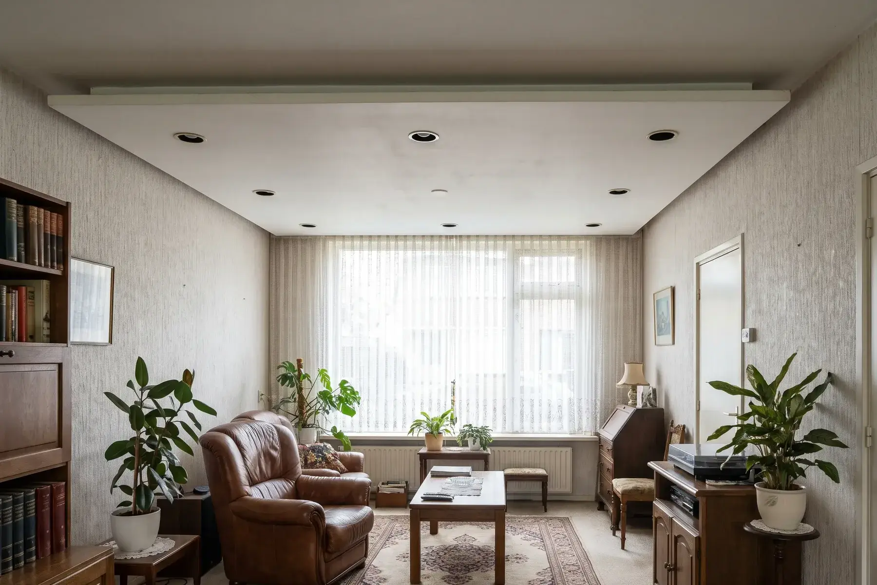 Woonkamer uit de jaren zeventig met een verlaagd plafond van gipsplaat en inbouwspots